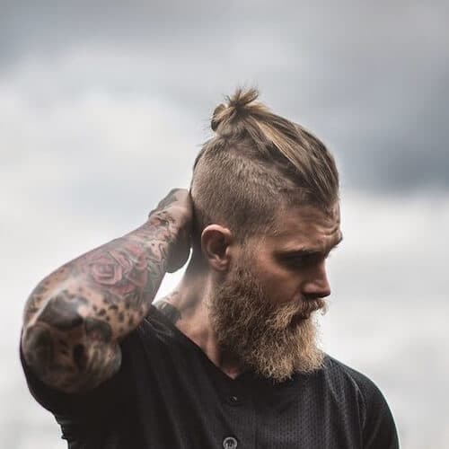 man with tattoos and a high and tight bun