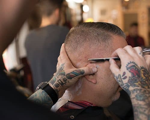 hairstylist with tattoo using a razor