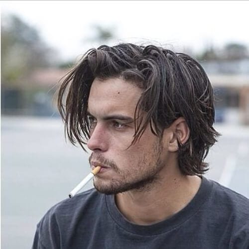 A man smoking with his 90s layered hairstyle