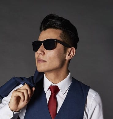 a man wearing sunglasses and pulling off a drop fade cut