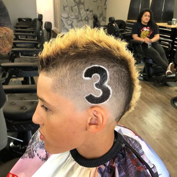Bleached Mohawk with Side Design- a man wearing a barber's cape Baseball Haircuts