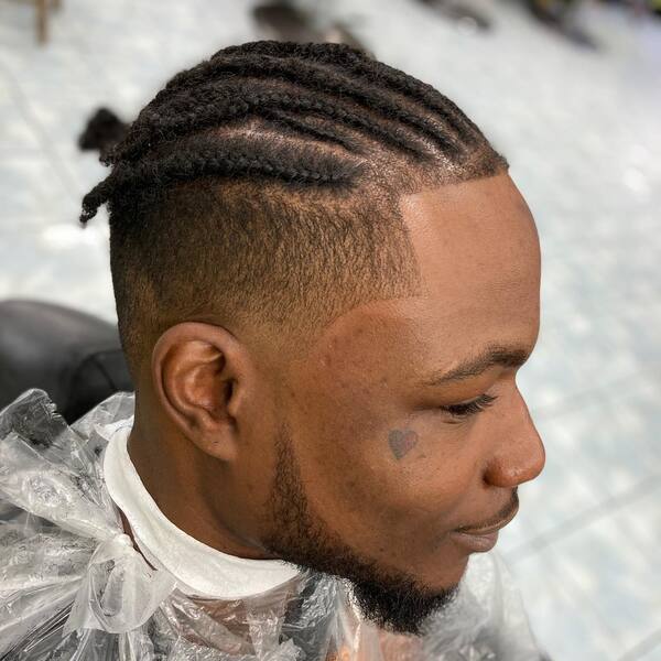 Cornrow Afro Braids with High Taper Fade- a man wearing a cellophane barber's cape