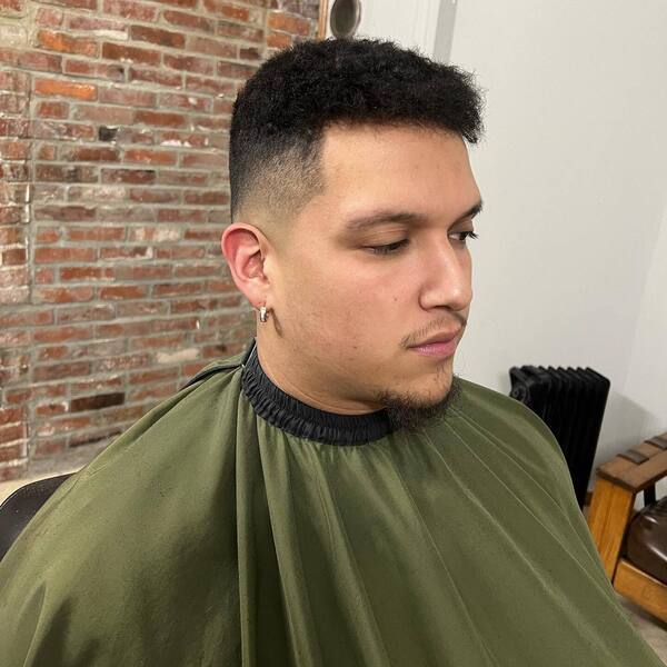 Curly Top Fade- a man wearing a green barber's cape