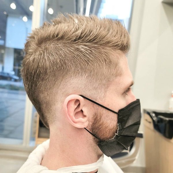 Faux Hawk with Low Fade- a man wearing a white barber's cape