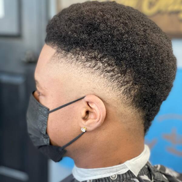 Kinky Curl Faux Hawk with Low Fade- a man wearing a black face mask and a black barber's cape