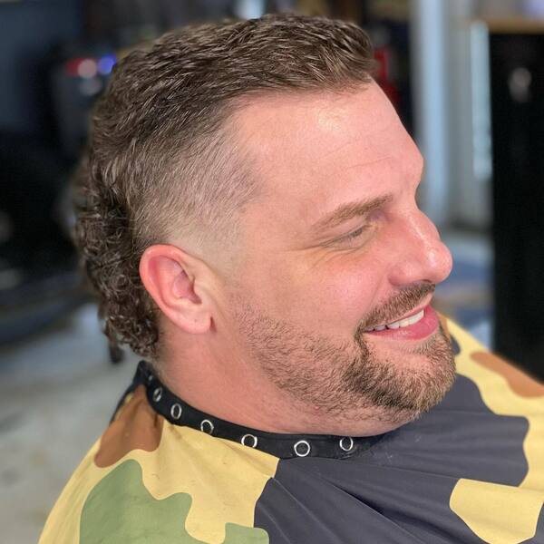 Mullet with Skin Fade- a man wearing a barber's cape Baseball Haircuts