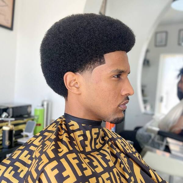 Shape Up Hairstyles for Black Men- a man wearing a yellow barber's cape