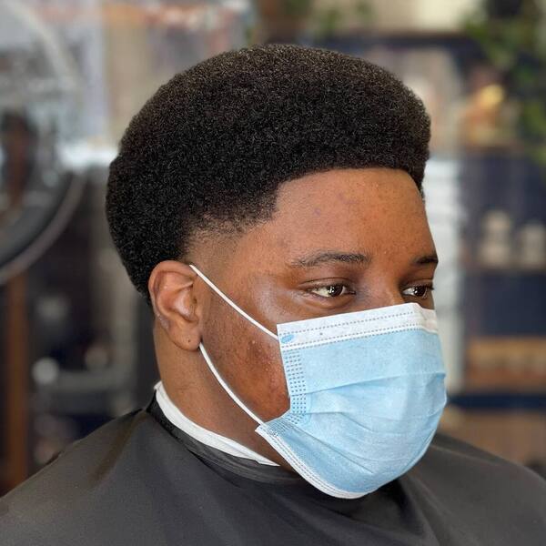 Shape Up Afro with Taper Fade- a man wearing a black barber's cape