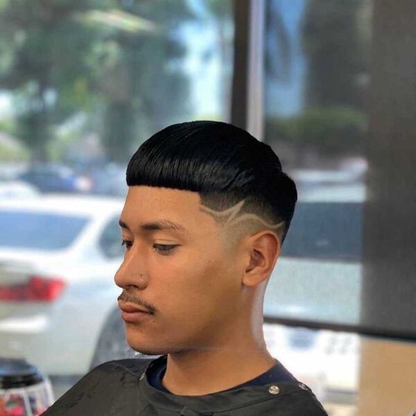 a man wearing a black barber's cape has a edgar cut on low fade with line up
